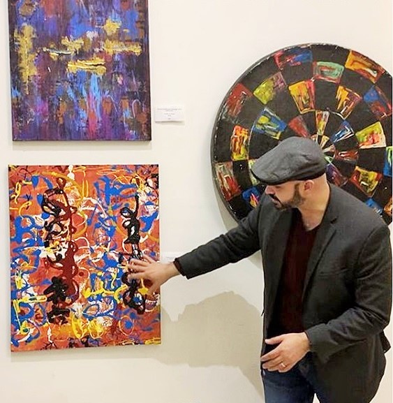 Brandon Aday at Pridelines Gallery during Miami Art Week, standing beside one of his works.