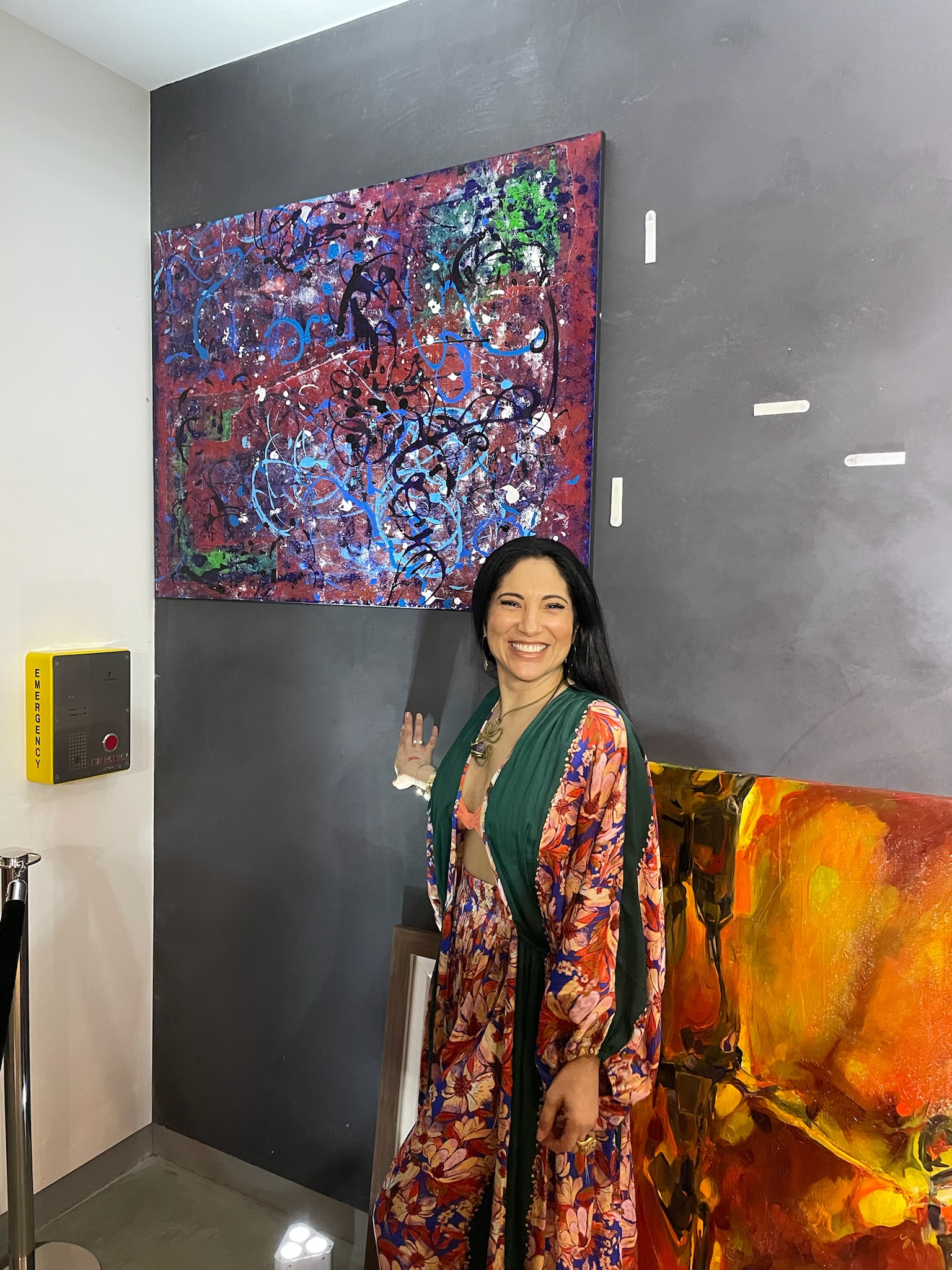 A collector stands beside a newly placed canvas on a gallery wall.